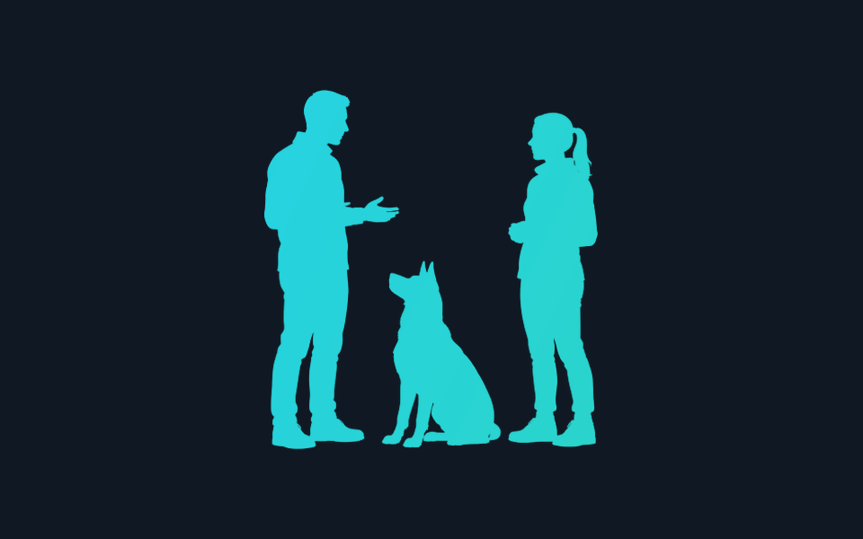 Two people facing one another with a seated dog between them.